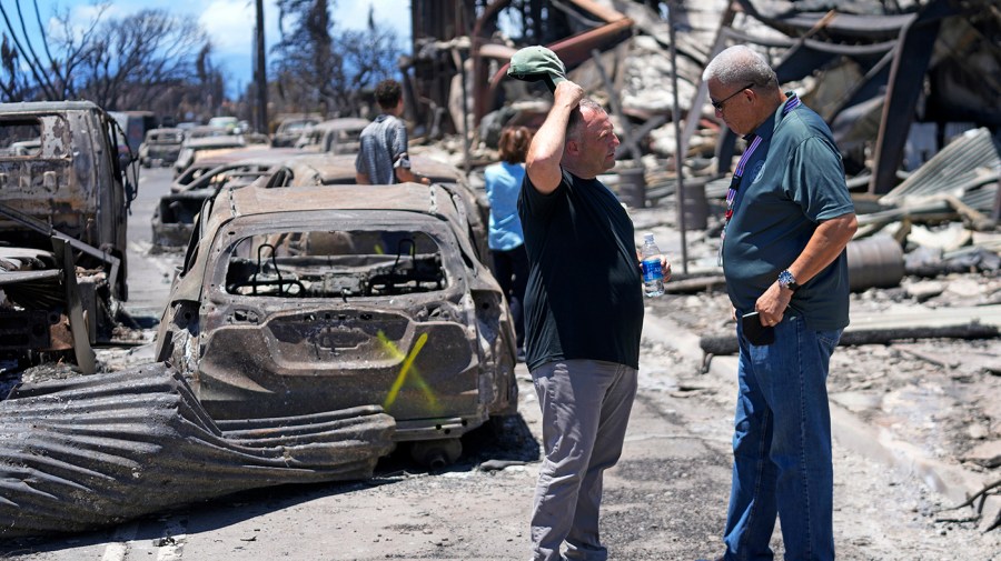 Governor of Hawaii Josh Green, left, and Maui County Mayor Richard Bissen, Jr., speak during a tour of wildfire damage on Saturday, Aug. 12, 2023, in Lahaina, Hawaii.