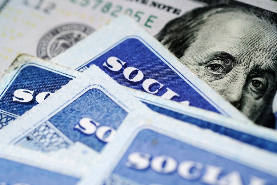 A stack of Social Security identification cards are placed on top of U.S. currency.