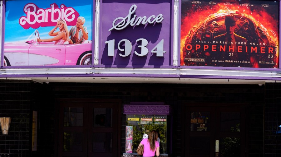 A patron buys a movie ticket underneath a marquee featuring the films "Barbie" and "Oppenheimer" at the Los Feliz Theatre, Friday, July 28, 2023, in Los Angeles. (AP Photo/Chris Pizzello)