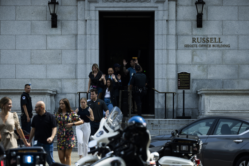 Staffers raise their hands leaving the Russell Senate Office Building