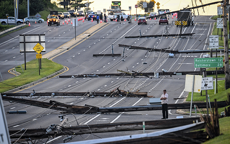 Looking east from Route 97, a man stands in the field of downed power lines and poles in the middle of a closed highway