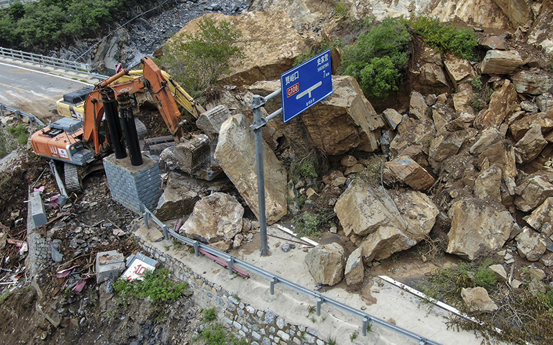 Heavy machinery remove rocks fallen on a road