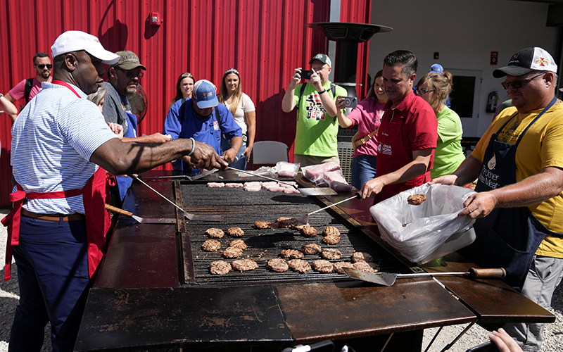 Republican presidential candidate Sen. Tim Scott (R-S.C.) works the grill at the Iowa Pork Producers tent