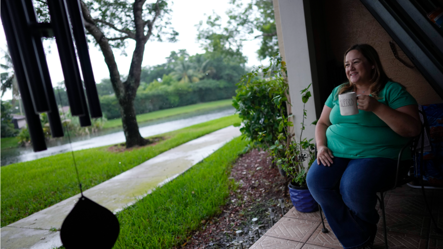 Melissa Lombana, 43, a high school teacher and mountain bike enthusiast, sits on the patio of her one-bedroom apartment in Miramar, Fla., Wednesday, July 26, 2023. Lombana's rent has increased each of the last two years and now amounts to nearly half her monthly income. "In a year, I will not be able to afford living here at all," she said. (AP Photo/Rebecca Blackwell)