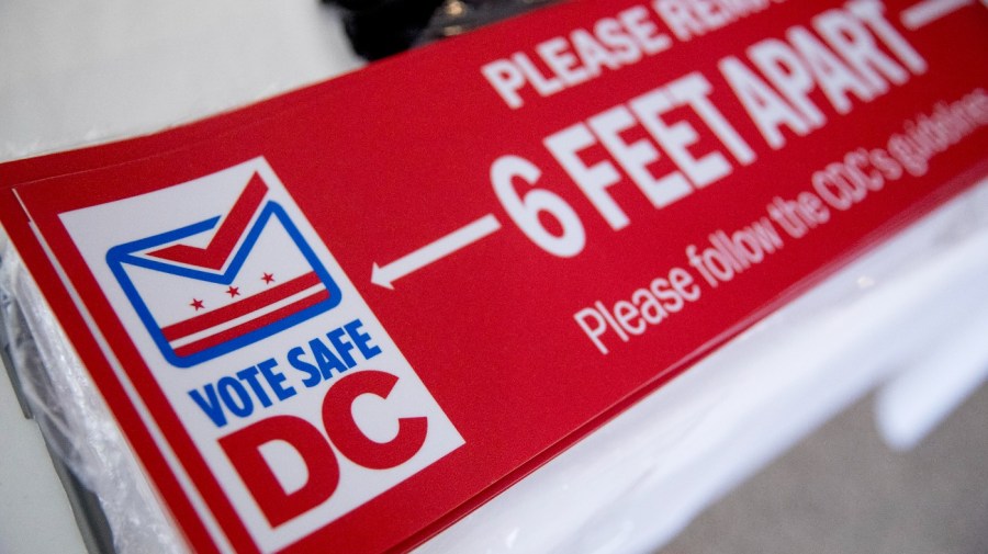 Social distancing stickers are visible at a voting center during primary voting in Washington, Tuesday, June 2, 2020. (AP Photo/Andrew Harnik)