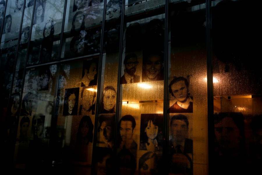 Photographs of people who disappeared during Argentina's bloody dictatorship (1976-1983) hang in the window at the former Argentine Navy School of Mechanics, now the Human Rights Museum, in Buenos Aires, Argentina, Thursday, Aug. 17, 2023. The Grandmothers of the Plaza de Mayo estimates around 500 children were snatched from their parents during the dictatorship, and the group has located 133 grandchildren through genetic analysis. (AP Photo/Natacha Pisarenko)