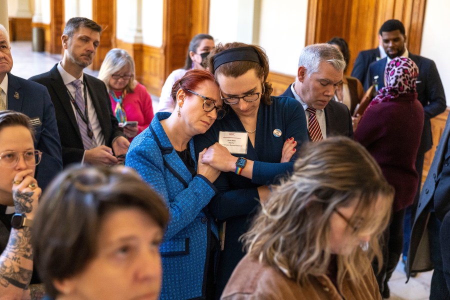 FILE - Jennifer Bowie, center left, and Aaron Baker, center right, become emotional while watching discussion of SB 140 on a video monitor in the Capitol before it gets final approval at the state Senate in Atlanta, Tuesday, March 21, 2023. A federal judge on Tuesday, Sept. 5, allowed Georgia to resume enforcing a ban on hormone replacement therapy for transgender people under 18. Judge Sarah Geraghty put her previous order blocking the ban on hold after a federal appeals court allowed Alabama to enforce a similar restriction. (Arvin Temkar/Atlanta Journal-Constitution via AP, File)