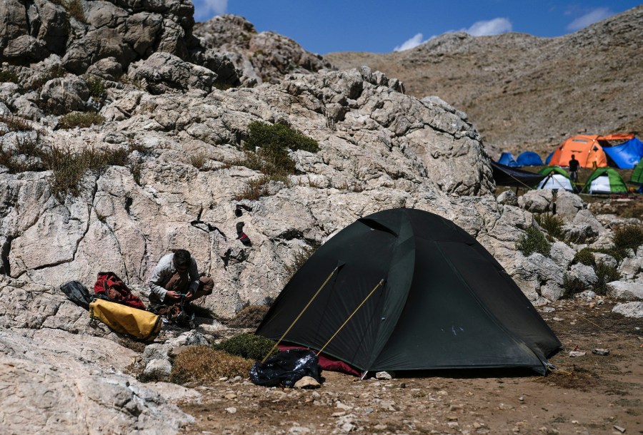 A rescuer works on her hiking gear in the European Cave Rescue Association (ECRA) members, camp next to the Morca cave during a rescue operation near Anamur, south Turkey, Saturday, Sept. 9, 2023. American researcher Mark Dickey, 40, who fell ill almost 1,000 meters (more than 3,000 feet) below the entrance of a cave in Turkey, has recovered sufficiently enough to be extracted in an operation that could last three or four days, a Turkish official was quoted as saying on Friday. (AP Photo/Khalil Hamra)