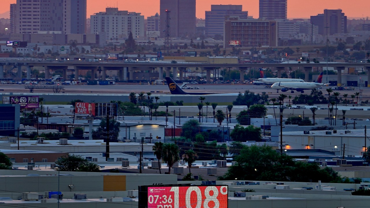 FILE - A sign displays an unofficial temperature as jets taxi at Sky Harbor International Airport at dusk, July 12, 2023, in Phoenix. (AP Photo/Matt York, File)