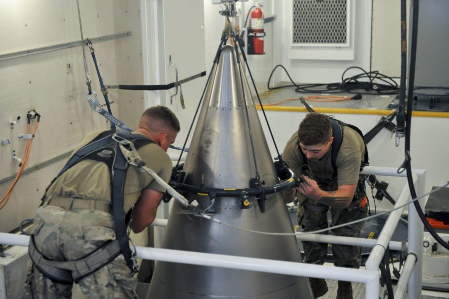 Two airmen secure a titanium shroud at the top of a Minuteman III intercontinental ballistic missile.