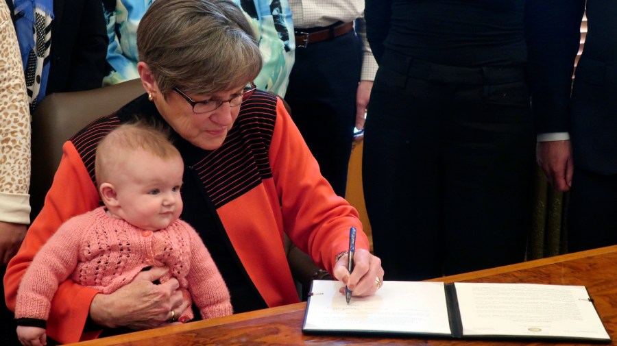 Kansas Gov. Laura Kelly holds her granddaughter, Rory, as she signs an executive order establishing a task force on child care issues, Tuesday, Jan. 10, 2023, at the Statehouse in Topeka, Kan.