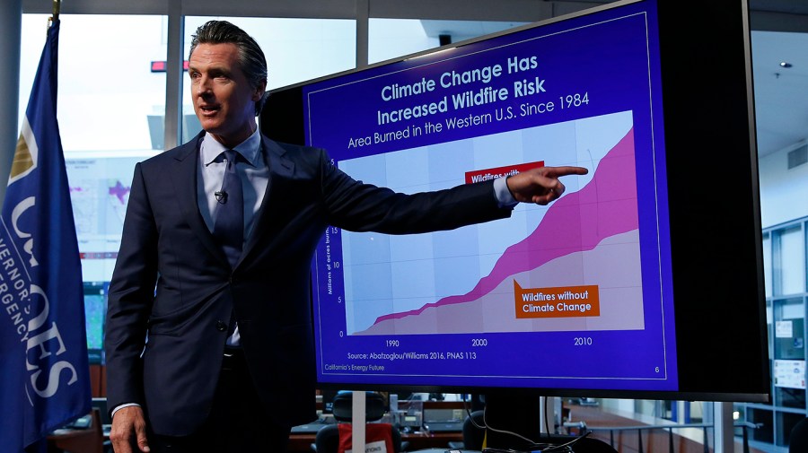 California Gov. Gavin Newsom points to a graph showing the increased in the risk to wildfires due to climate change during a news conference in Rancho Cordova, Calif., April 12, 2019. Newsom says he plans to sign into law a pair of climate-focused bills intended to force major corporations to be more transparent about greenhouse gas emissions and financial risks stemming from global warming.