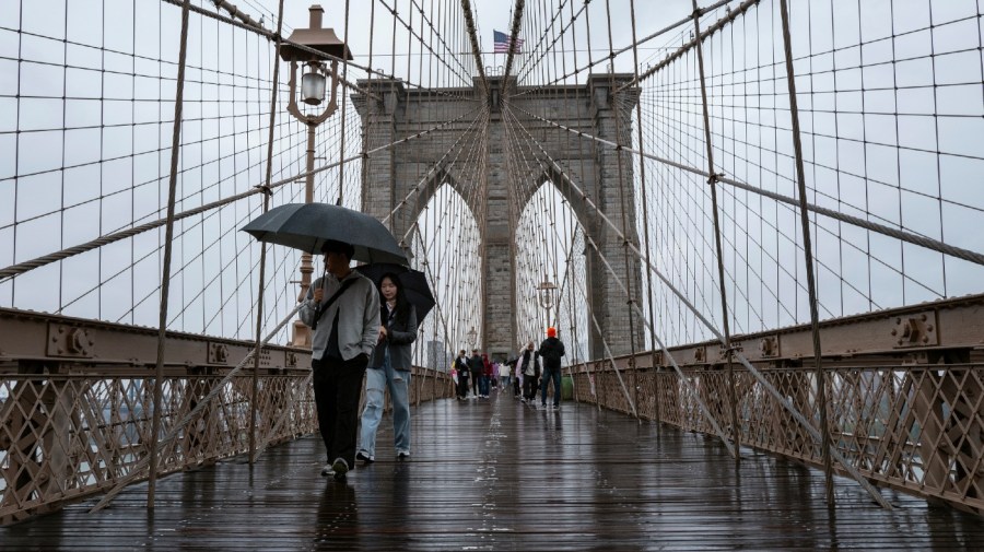 Visitors brave the rain as they visit the Brooklyn Bridge walkway in New York, Tuesday, Sept. 26, 2023.