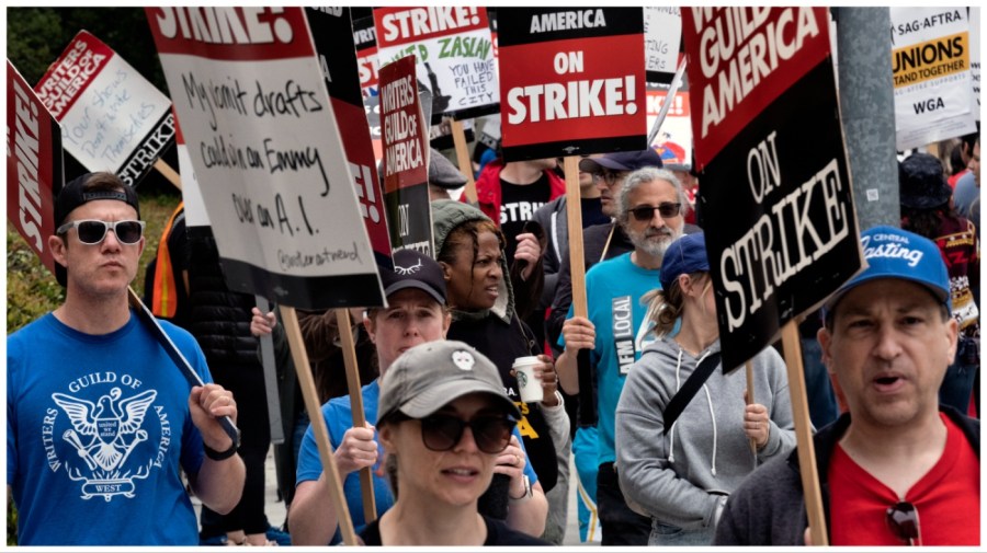 FILE -Picketers pass near a studio entrance during a Writers Guild rally outside Warner Bros. Studios, Wednesday, May 24, 2023, in Burbank, Calif. As a strike drags on, about 1,000 Hollywood writers and their supporters have marched and rallied in Los Angeles for a new contract with studios that includes the payment guarantees and job security they say they deserve. Speakers at Wednesday's event on June 21, emphasized the solidarity the Writers Guild of America has received from other unions. (AP Photo/Richard Vogel, File)