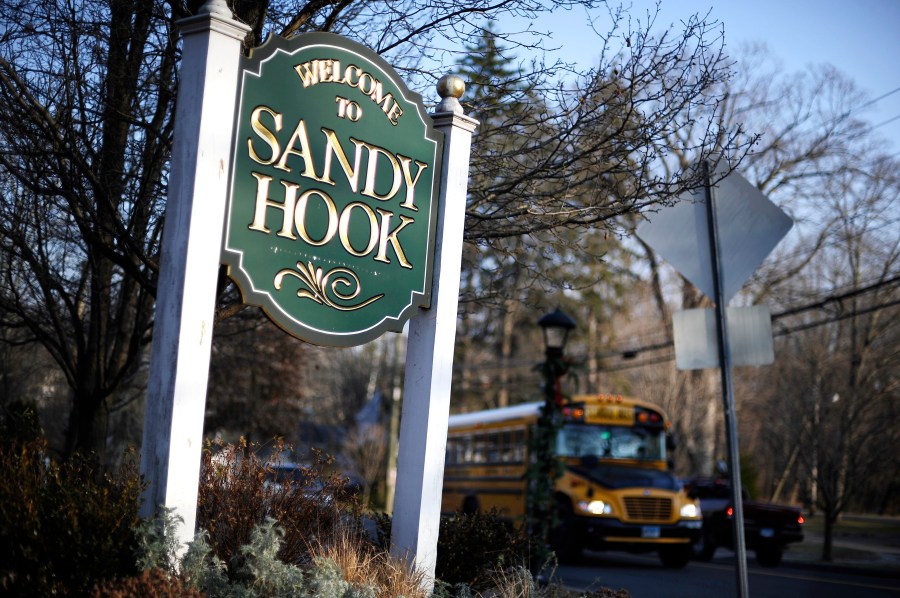 FILE - A bus drives past a sign reading Welcome to Sandy Hook in Newtown, Conn., Dec. 4, 2013. Connecticut’s most wide-ranging gun control measure since the 2013 law enacted after the Sandy Hook Elementary School shooting is taking effect Sunday, Oct. 1, 2023. The new law, signed by Democratic Gov. Ned Lamont in June, bans the open carrying of firearms and prohibits the sale of more than three handguns within 30 days to any one person, with some exceptions for instructors and others. (AP Photo/Jessica Hill, File)