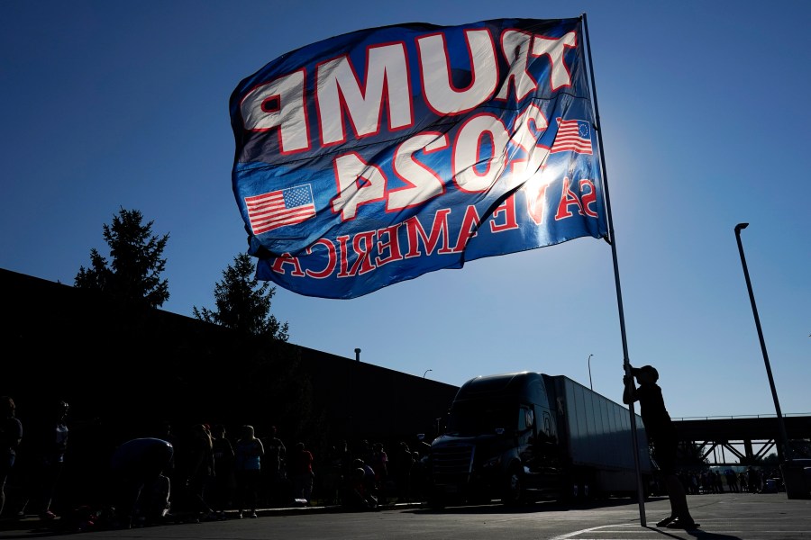 A supporter of former President Donald Trump holds a flag before a rally, Sunday, Oct. 1, 2023, in Ottumwa, Iowa. (AP Photo/Charlie Neibergall)