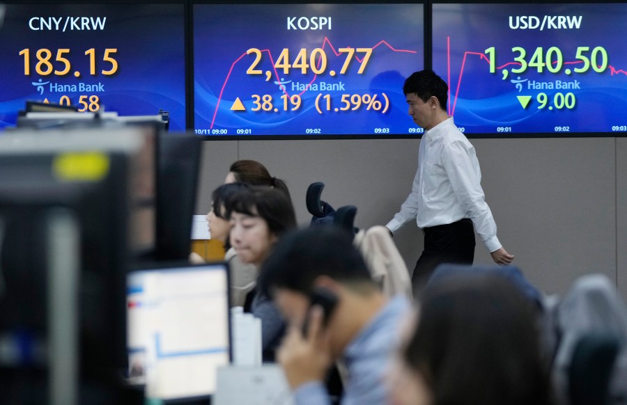 A currency trader passes by the screens showing the Korea Composite Stock Price Index (KOSPI), center, and the foreign exchange rate between U.S. dollar and South Korean won, right, at the foreign exchange dealing room of the KEB Hana Bank headquarters in Seoul, South Korea, Wednesday, Oct. 11, 2023. Shares are higher in Asia, tracking Wall Street gains following an easing of pressure from the bond market. (AP Photo/Ahn Young-joon)