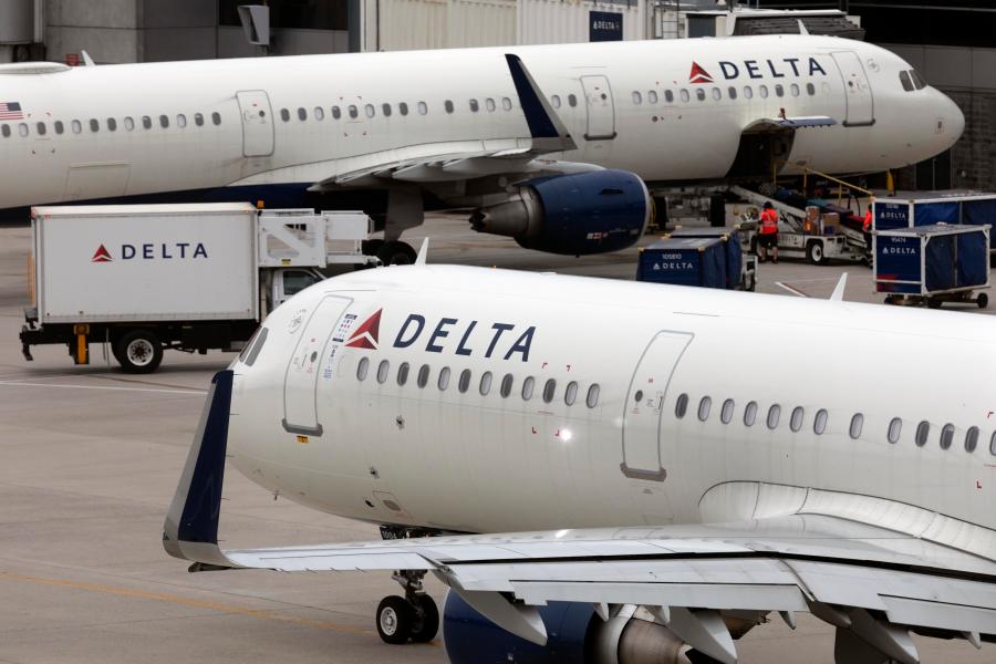 Two Delta Air Lines planes are seen on the tarmac at an airport.