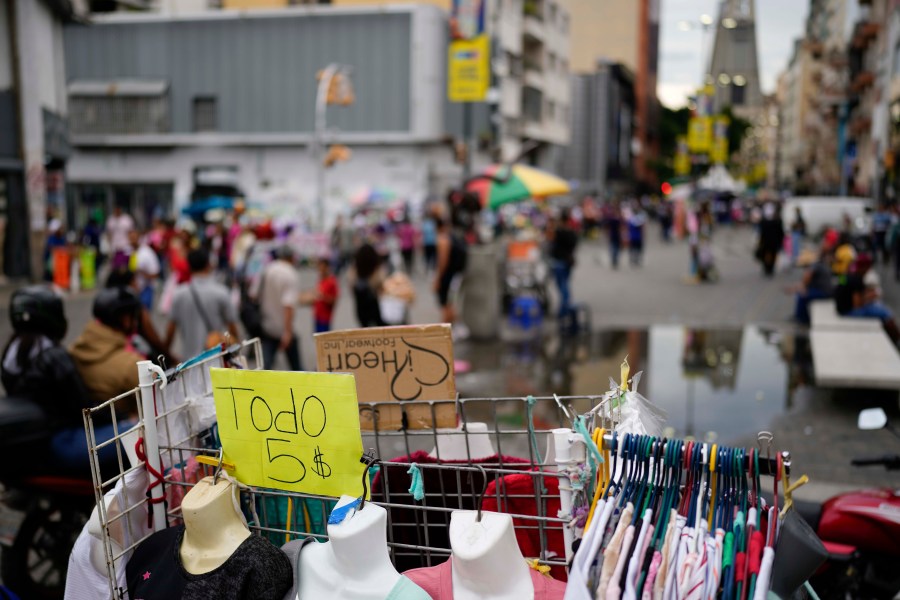 FILE - A sign announces "All for five dollars" on a rack outside a store in Caracas, Venezuela, Oct. 3, 2023. (AP Photo/Matias Delacroix, File)