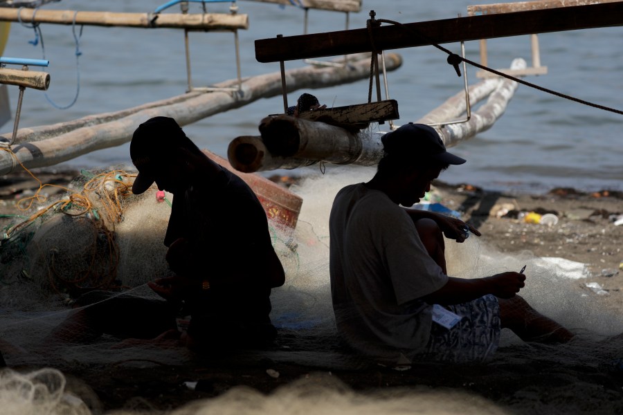 FILE - Fishermen work on nets as they spend time on the shores of their coastal village in Cavite province, south of Manila, Philippines, on May 7, 2020. Canada will help the Philippines detect illegal fishing with its satellite surveillance system under a new agreement, Philippine officials said Monday, Oct. 16, 2023. (AP Photo/Aaron Favila, File)