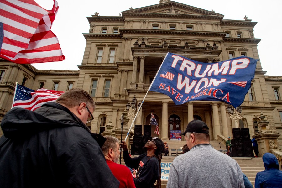 FILE - A protester waves a Trump flag during rally at the Michigan Capitol, Oct. 12, 2021, in Lansing, Mich. James Renner, a Michigan Republican accused of participating in a fake elector plot, had all criminal charges dropped Thursday, Oct. 19, 2023, after the state Attorney General's office said a cooperation deal was reached. Michigan was one of seven states where supporters of then-President Donald Trump signed certificates that falsely stated he won their states. (Jake May/The Flint Journal via AP, File)