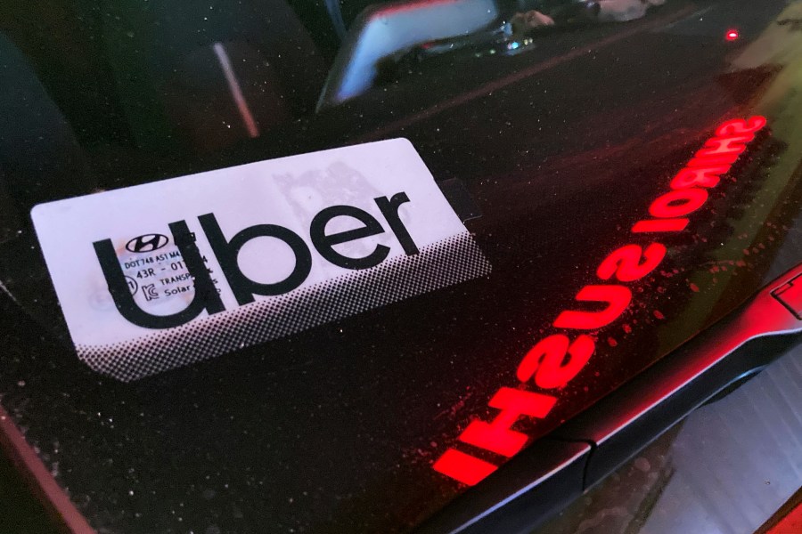 File - An Uber sign is displayed inside a car in Glenview, Ill., on Dec. 17, 2022. Ride-hailing companies Uber and Lyft will pay a combined $328 million to settle wage theft claims in New York, Attorney General Letitia James announced Thursday. (AP Photo/Nam Y. Huh, File)