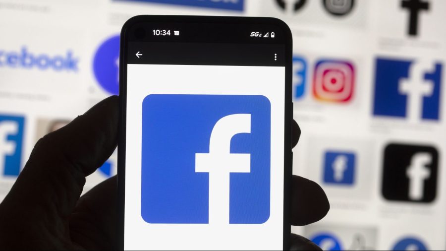 FILE - The Facebook logo is seen on a cell phone in Boston, USA, Friday, Oct. 14, 2022. The owner of Facebook and Instagram says it'll put labels on political ads created using artificial intelligence. The new policy announced Wednesday by Meta goes into effect Jan. 1 and will apply worldwide. (AP Photo/Michael Dwyer, File)