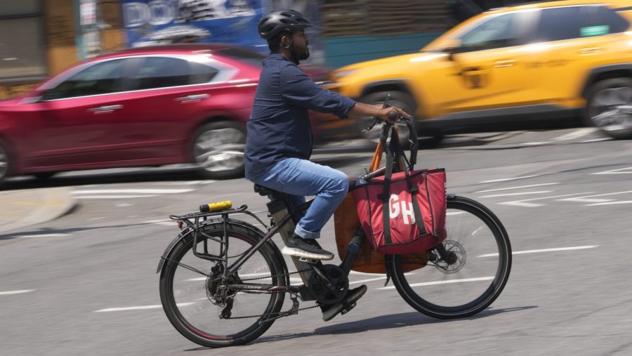 FILE - A delivery worker rides a motorized bicycle, July 25, 2023, in New York. On Monday, Nov. 13, New York City officials said that retailers and food delivery companies must do more to halt the proliferation of unsafe e-bike and e-scooter batteries after a fire blamed on an electric scooter's lithium ion battery killed three people over the weekend. (AP Photo/Seth Wenig, File)