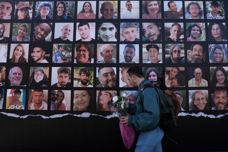 A man walks past a billboard calling for the return of about 240 hostages who were abducted during the Oct. 7, Hamas attack on Israel. in Jerusalem on Friday, Nov. 24, 2023. Friday marks the start of a four-day cease-fire in the Israel-Hamas war, during which the Gaza militants pledged to release 50 hostages in exchange for 150 Palestinians imprisoned by Israel. (AP Photo/Mahmoud Illean)