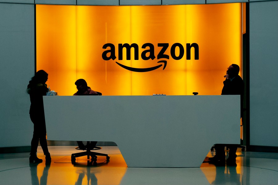 FILE - In this Feb. 14, 2019 file photo, people stand in the lobby for Amazon offices in New York. Amazon finally has its answer to ChatGPT. The tech giant said Tuesday, Nov. 28, 2023, it will launch Q – a generative-AI powered chatbot for businesses. (AP Photo/Mark Lennihan, File)