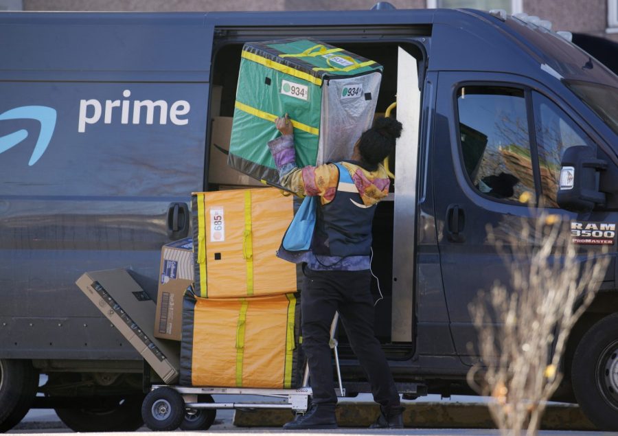 An Amazon Prime delivery person struggles with packages while making a stop at a high-rise apartment building on Tuesday, Nov. 28, 2023, in Denver. (AP Photo/David Zalubowski)