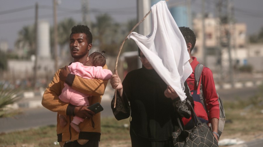 A woman holds up a stick with a shirt attached as a white flag to prevent being shot, as Palestinians flee Gaza City to the southern Gaza Strip on Salah al-Din street in Bureij, Nov. 7, 2023.