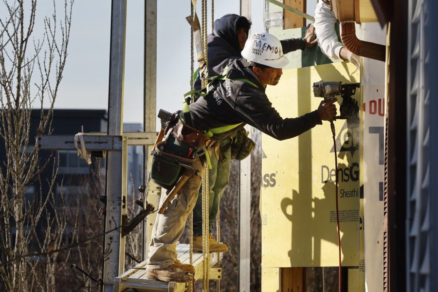 Workers apply sheathing to the exterior of a new multifamily residential building, Friday, Nov. 3, 2023, in the East Boston neighborhood of Boston. On Friday, the U.S. government issues its November jobs report. (AP Photo/Michael Dwyer)