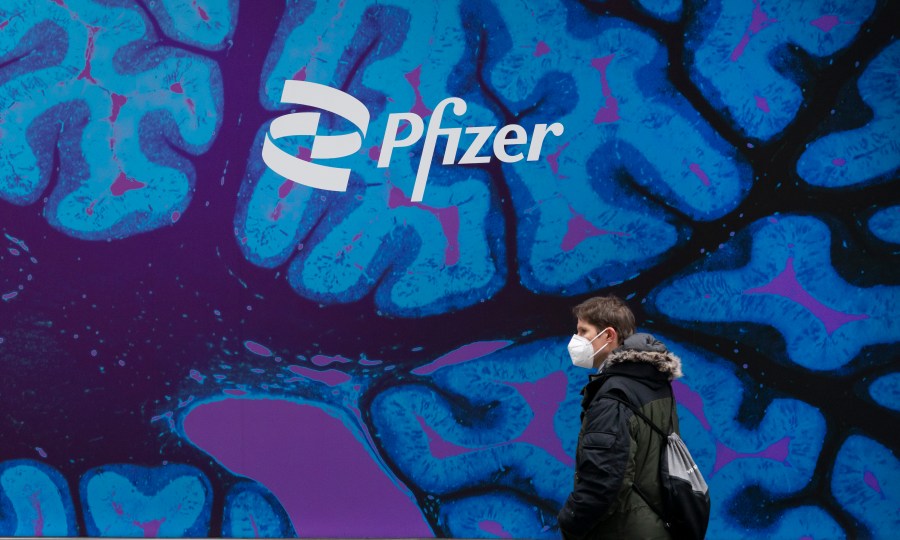 FILE - A man walks by Pfizer headquarters, Friday, Feb. 5, 2021 in New York. Pfizer released a financial outlook for next year that that doesn't match with Wall Street expectations as sales of COVID-19 products slide. Shares tumbled more than 7% before the opening bell Wednesday, Dec. 13, 2023. (AP Photo/Mark Lennihan, File)