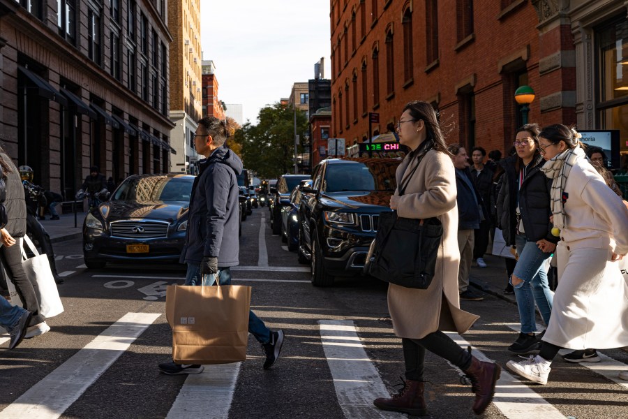 FILE - Shoppers holding bags cross Prince Street on Black Friday in New York, Friday, Nov. 24, 2023. If you’re planning on grabbing groceries or doing some other shopping this New Year’s Day, it’s wise to double check stores’ hours.(AP Photo/Peter K. Afriyie, File)