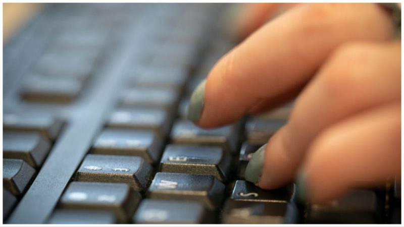 A close-up shows fingers typing on a computer keyboard.