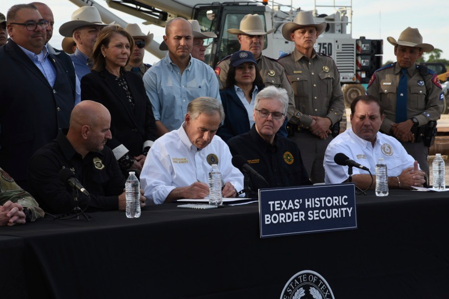 FILE - Texas Gov. Greg Abbott signs three bills into law at a border wall construction site in Brownsville, Texas, Dec. 18, 2023, that will broaden his border security plans and add funding for more infrastructure to deter illegal immigration. The Justice Department on Wednesday, Jan. 3, 2024, sued Texas over a new law that would allow police to arrest migrants who enter the U.S. illegally, taking Abbott to court again over his escalating response to border crossers arriving from Mexico. (AP Photo/Valerie Gonzalez, File)