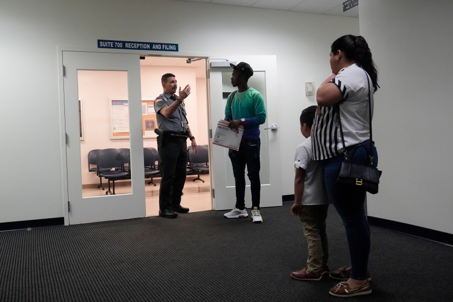 An officer directs people to a courtroom, Wednesday, Jan. 10, 2024, in an immigration court in Miami. Immigration courts are buckling under an unprecedented 3 million pending cases, most of them newly arrived asylum-seekers. The number of migrants trying to fight their deportation in front of a US judge has grown by 50% in less than a year. (AP Photo/Wilfredo Lee)