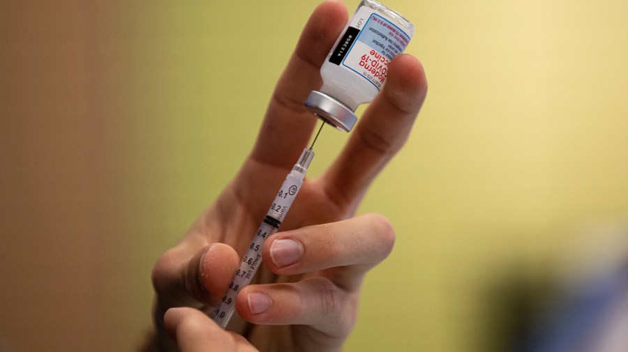 A person prepares a dose of a Moderna COVID-19 vaccine.