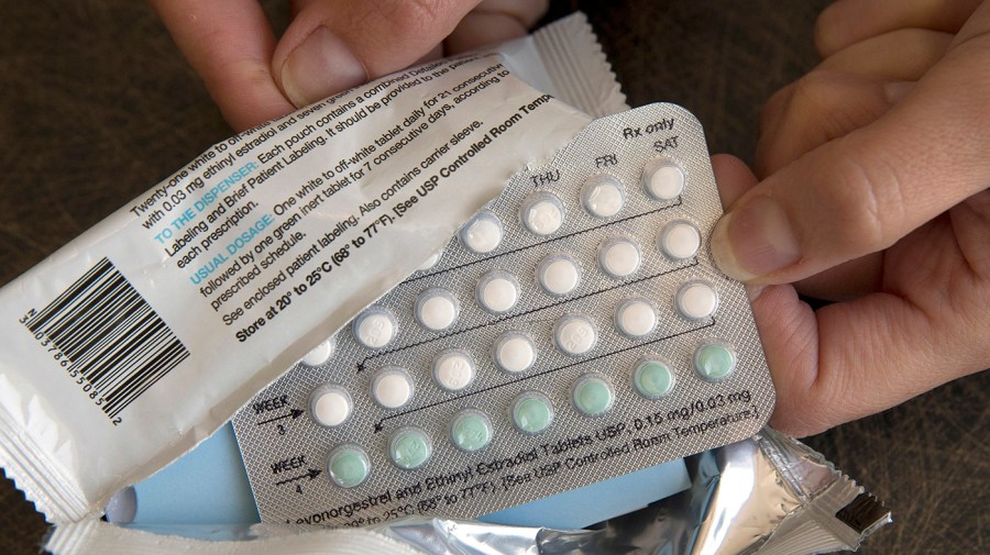 A person opens a package of a one-month supply of hormonal birth control.