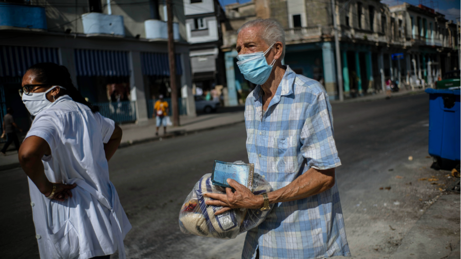 Leandro Rodriguez, 69, carries a package of food donated by several countries after picking it up at state-run "bodega," where residents pick up their monthly rations of government subsidized staples, in Havana, Cuba, Friday, Aug. 13, 2021.