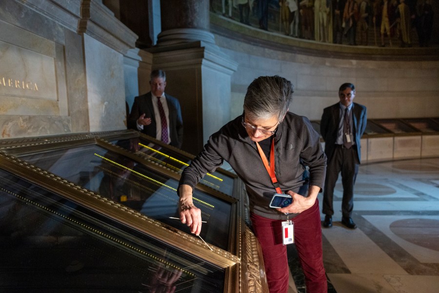 Amy Lubick, a supervisory conservator at the National Archives, runs a cotton swab over a display case that held the U.S. Constitution at National Archives in Washington on Thursday, Feb. 15, 2024. The National Archives building and galleries were evacuated on Feb. 14 after two protesters dumped powder on the protective casing around the U.S. Constitution. (AP Photo/Amanda Andrade-Rhoades)