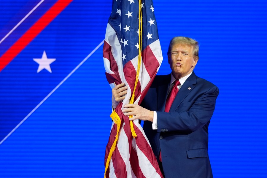 Republican presidential candidate former President Donald Trump hugs the flag as he speaks at the Conservative Political Action Conference, CPAC 2024, at National Harbor, in Oxon Hill, Md., Saturday, Feb. 24, 2024. (AP Photo/Alex Brandon)