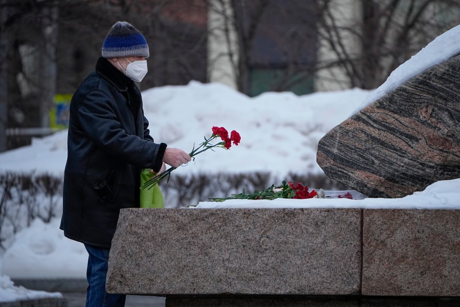 A man lays flowers to pay tribute to Alexei Navalny at the monument, a large boulder from the Solovetsky islands, where the first camp of the Gulag political prison system was established, near the historical Federal Security Service (FSB, Soviet KGB successor) building in Moscow, Russia, on Monday, Feb. 26, 2024. Navalny, 47, Russia's most well-known opposition politician, unexpectedly died on Feb. 16 in the penal colony, prompting hundreds of Russians across the country to stream to impromptu memorials with flowers and candles. (AP Photo/Alexander Zemlianichenko)