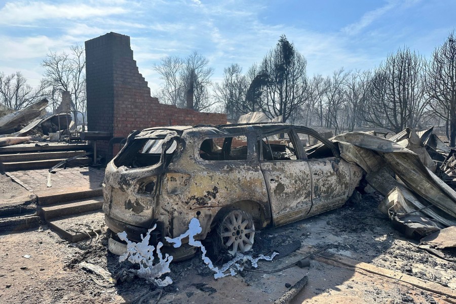 A burned car rests near the charred remains of a home outside of Canadian, Texas, Wednesday, Feb. 28, 2024, after a wildfire passed. A fast-moving wildfire burning through the Texas Panhandle grew into the second-largest blaze in state history Wednesday, forcing evacuations and triggering power outages as firefighters struggled to contain the widening flames. (AP Photo/Sean Murphy)