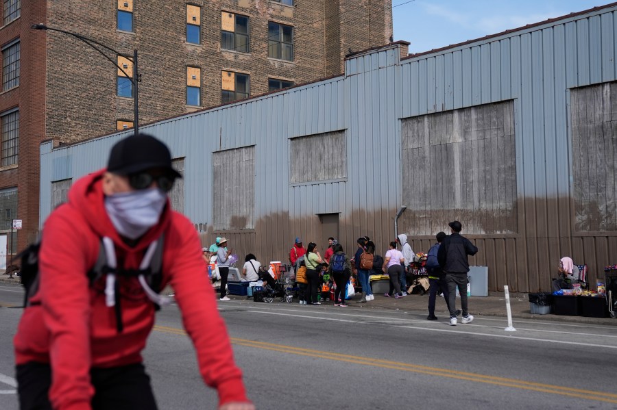 People hang around outside of a migrant shelter Wednesday, March 13, 2024, in the Pilsen neighborhood of Chicago. Multiple people living at the shelter for migrants have tested positive for measles since last week. A team from the Centers for Disease Control and Prevention is supporting local officials' response. (AP Photo/Erin Hooley)