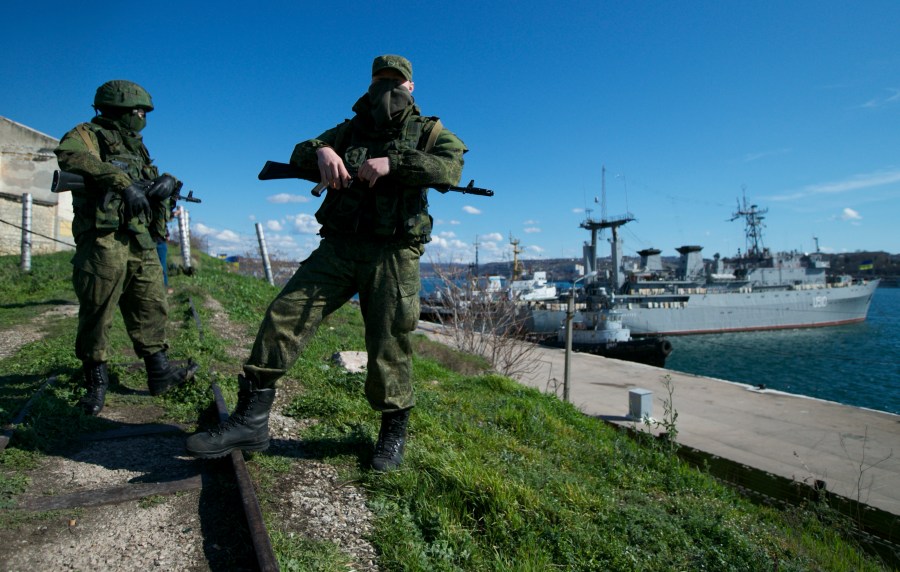 FILE - Russian soldiers guard a pier where two Ukrainian naval vessels are moored, in Sevastopol, Ukraine, on Wednesday, March 5, 2014. When Ukraine's Kremlin-friendly president was ousted in 2014 by mass protests that Moscow called a U.S.-instigated coup, Russian President Vladimir Putin responded by sending troops to overrun Crimea and staging a plebiscite on joining Russia, which the West dismissed as illegal. (AP Photo, File)