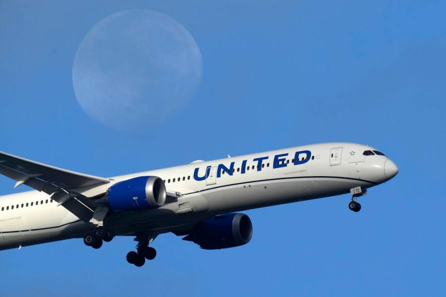 FILE - A United Airlines Boeing 787 approaches for landing in Lisbon, Sept. 2, 2023, with the setting moon in the background. Don't have enough airline miles for that free flight? United Airlines is now letting people pool and share their frequent-flyer points with family and friends, the airline announced Thursday, March 21, 2024. (AP Photo/Armando Franca, File)