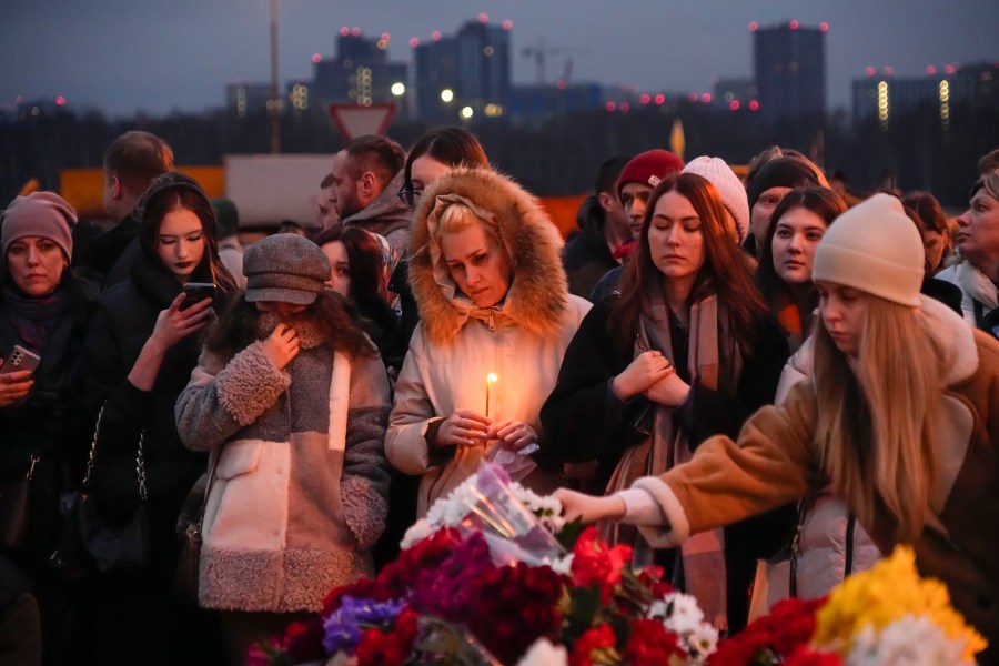 People lay flowers and light candles standing next to the Crocus City Hall, on the western edge of Moscow, Russia, Saturday, March 23, 2024. Russia's top state investigative agency says the death toll in the Moscow concert hall attack has risen to over 133. The attack Friday on Crocus City Hall, a sprawling mall and concert venue on Moscow's western edge, also left many wounded and left the building a smoldering ruin. (AP Photo/Alexander Zemlianichenko)