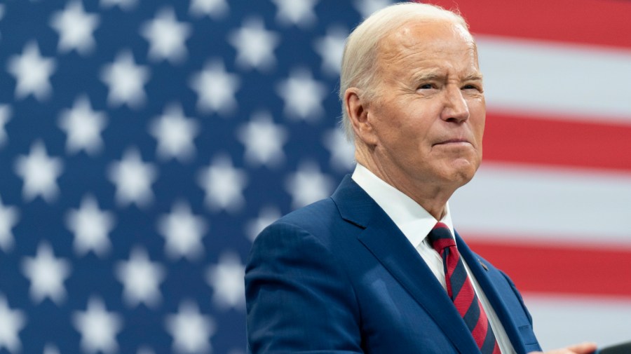 President Joe Biden delivers remarks with a large American flag visible behind him.